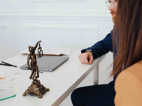 Professional setting with lawyers and Lady Justice statue discussing legal documents.