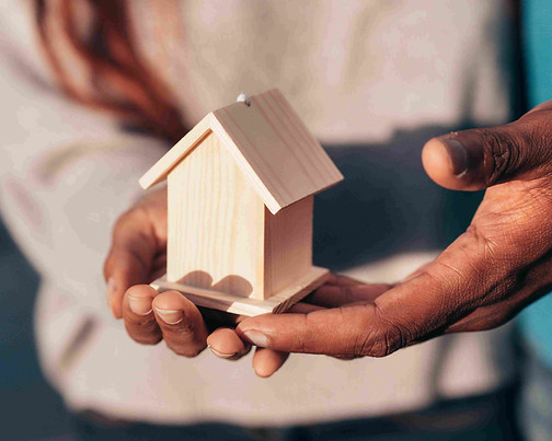 Hands holding a small wooden house representing the transfer of real estate through Florida probate summary administration