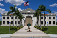 Palacio de Justicia del Condado de Okeechobee en Florida, que representa los servicios locales del Tribunal de Sucesiones, con arquitectura clásica blanca, palmeras y la bandera estadounidense