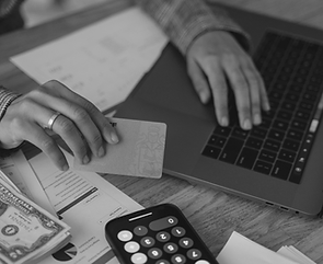 Person reviewing bills and financial documents while holding a payment card at a laptop, representing creditor claims, outstanding debts, and financial obligations in a Florida probate case.