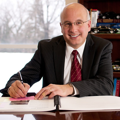 Business Professional at his desk in his office smiling while writing