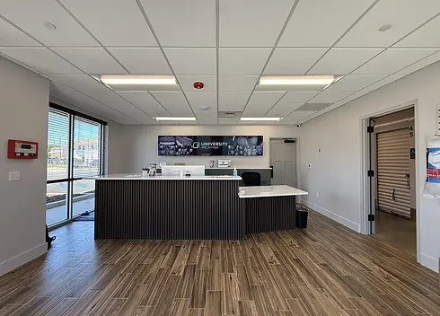 Modern office reception area at University Self Storage with front desk, branded wall display, and wood flooring
