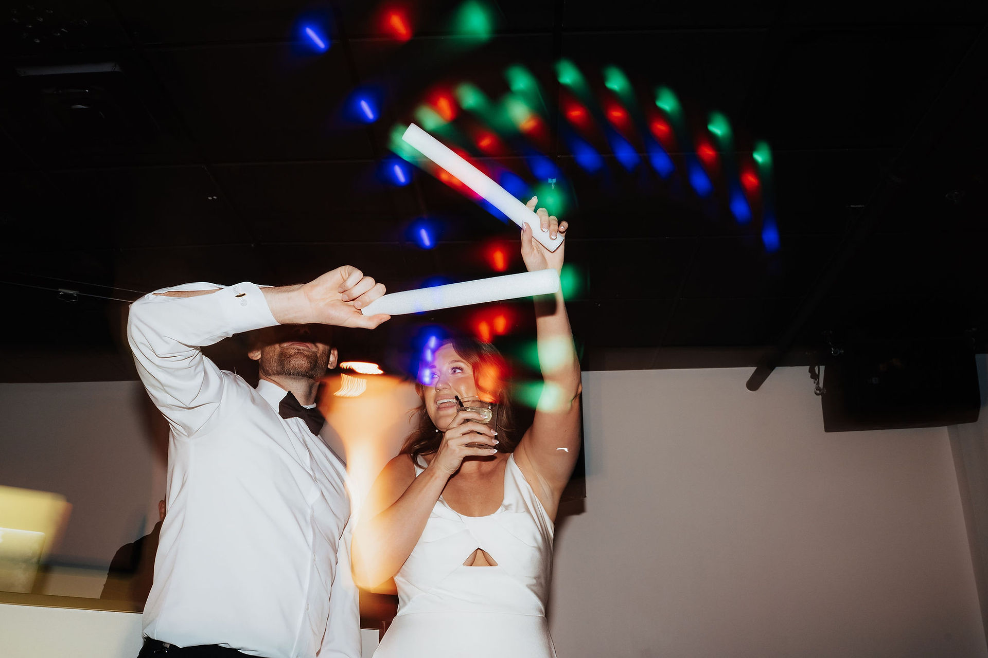 A bride and groom waving light sticks over their heads
