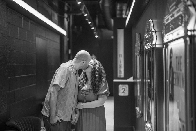 black and white photo of a couple kissing in a movie theater lobby