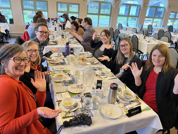 Groupe de personnes souriantes agitant la main, au repas.