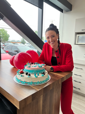 Femme souriante en rouge avec gâteau d'anniversaire et ballons