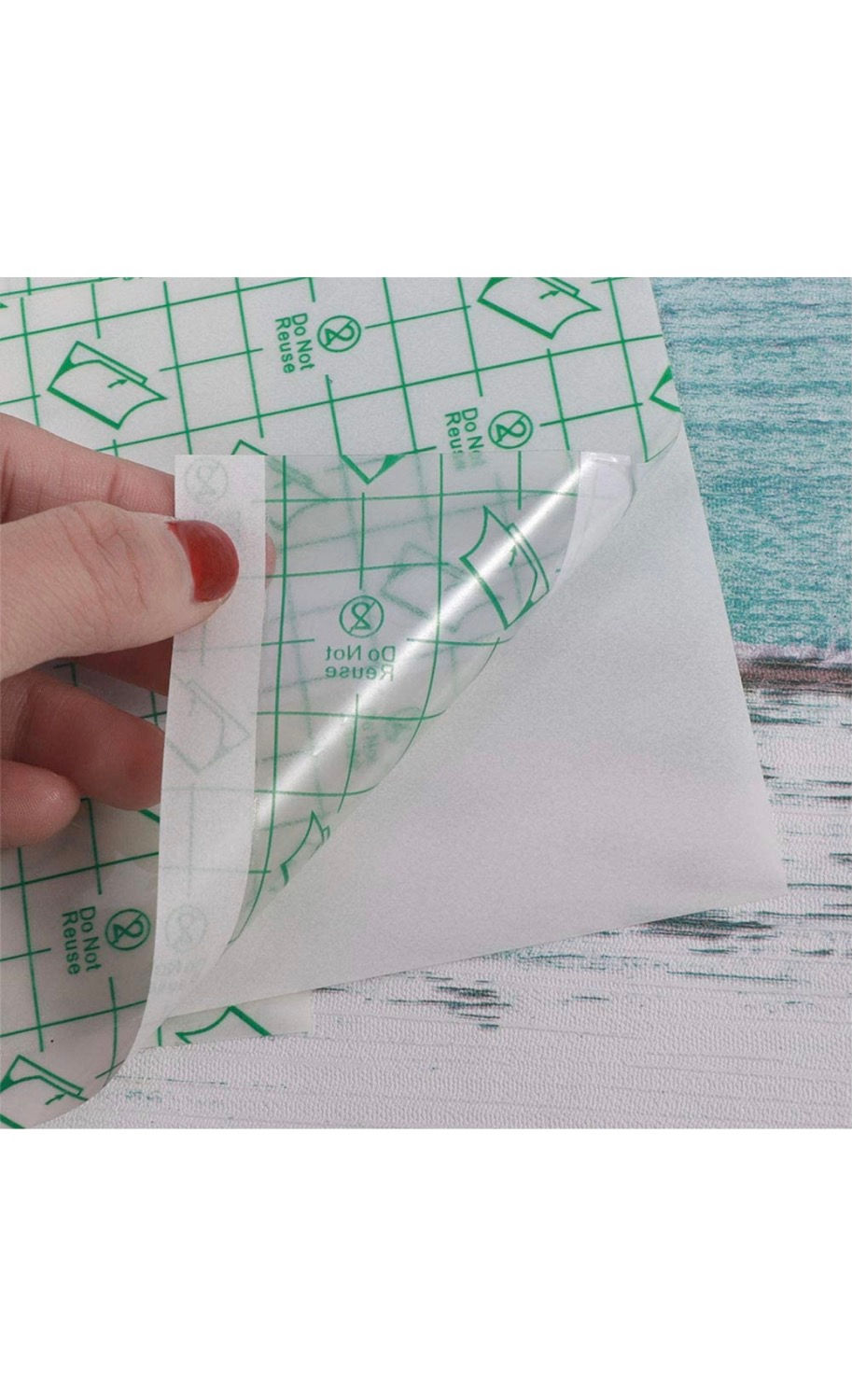 Miniatyrbild: Hand peeling off transparent bandage, green grid background, on wooden table.