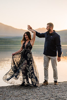 couple celebrates engagement with a sunset dance on Lake Mcdonalds rainbow rocks
