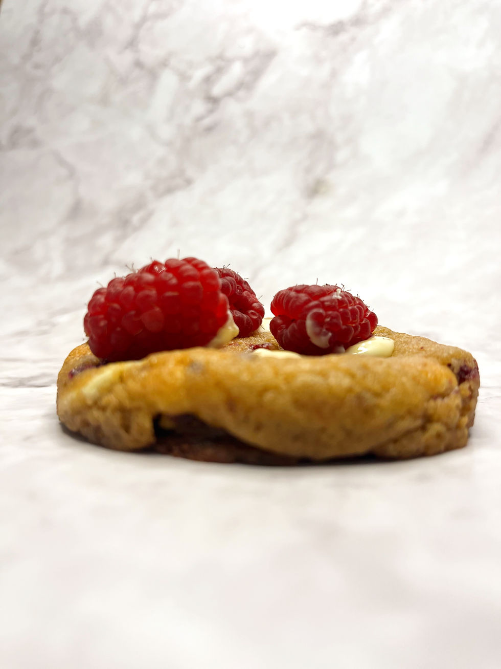 Cookie framboise chocolat blanc avec des framboises entières et du chocolat blanc fondant. Un délice fruité et crémeux.
