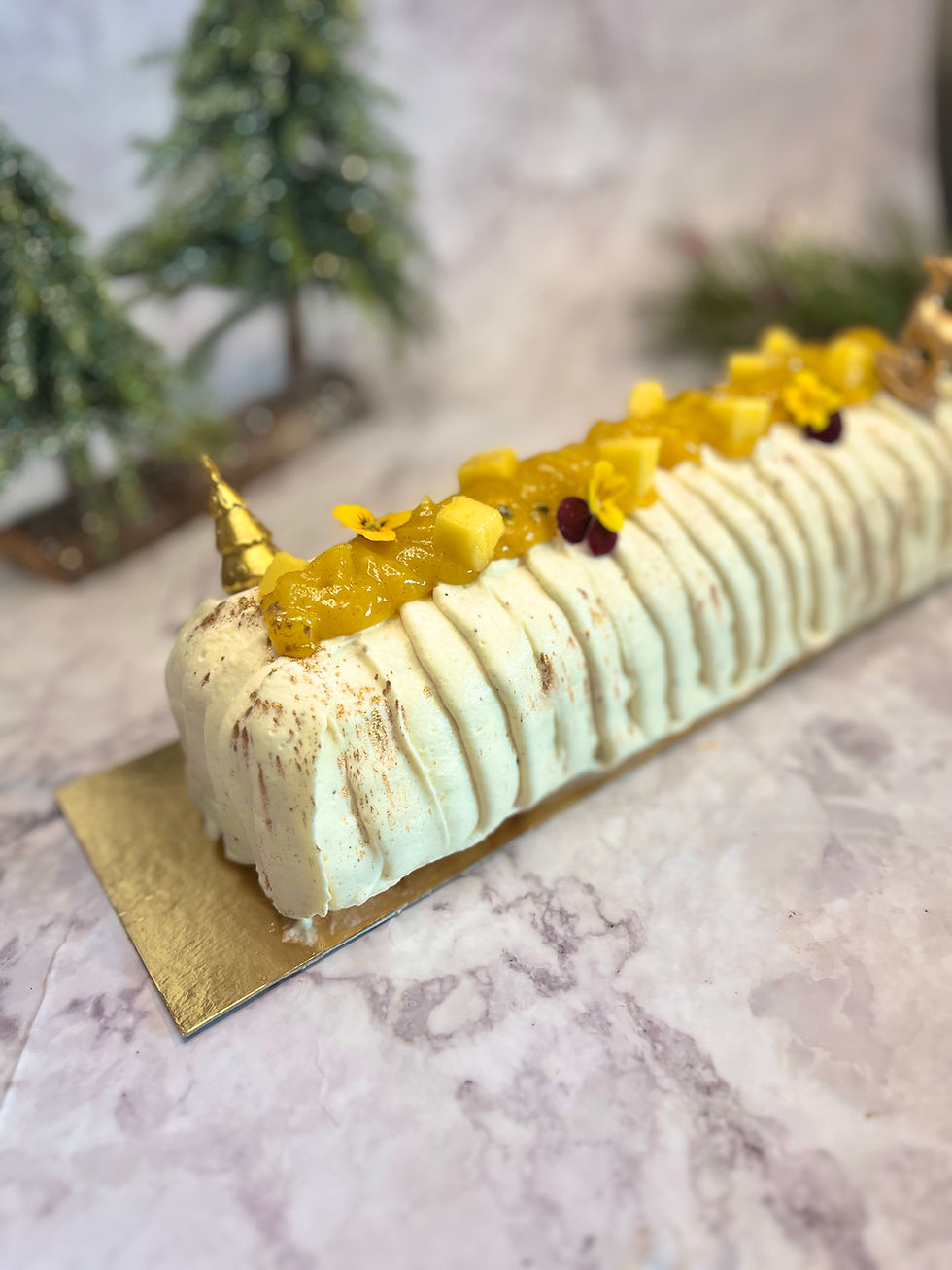 Bûche de Noël Mangue Passion Coco avec ganache montée, crémeux passion et croustillant praliné coco