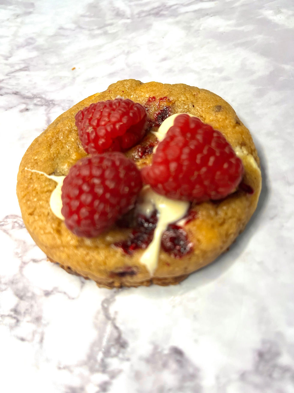 Cookie framboise chocolat blanc avec des framboises entières et du chocolat blanc fondant. Un délice fruité et crémeux.