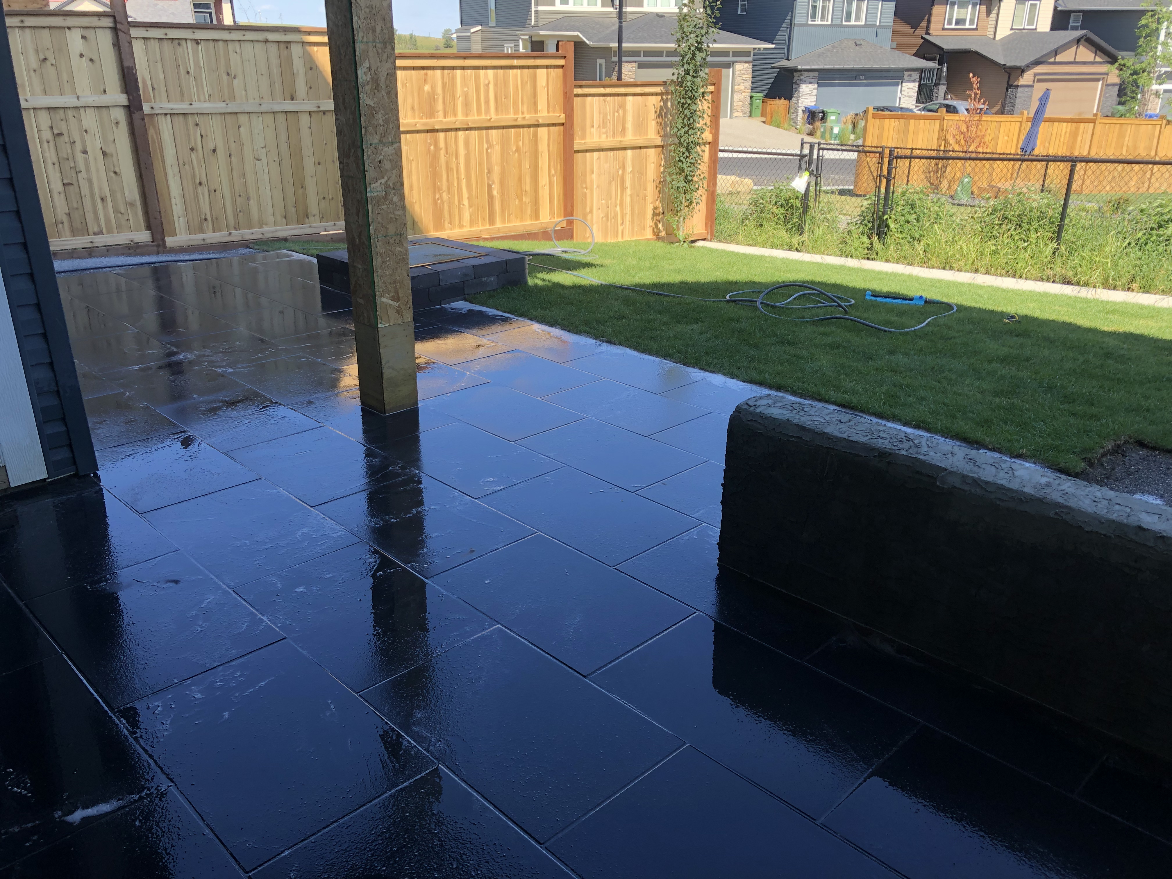 Paved patio, green lawn and timber privacy fencing