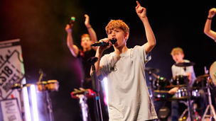 A young participant fronts a band and sings into a microphone