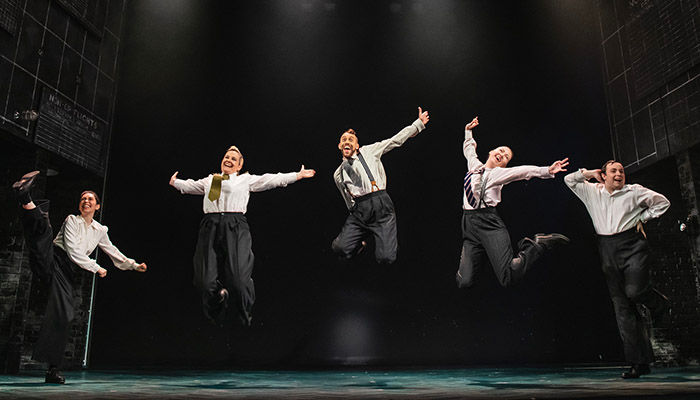 Five people jumping in the air on a WWII wartime stage set. Operation Mincemeat at war: l-r Claire-Marie Hall, Zoe Roberts, David Cumming, Natasha Hodgson and Jak Malone. Pic: Matt Crockett