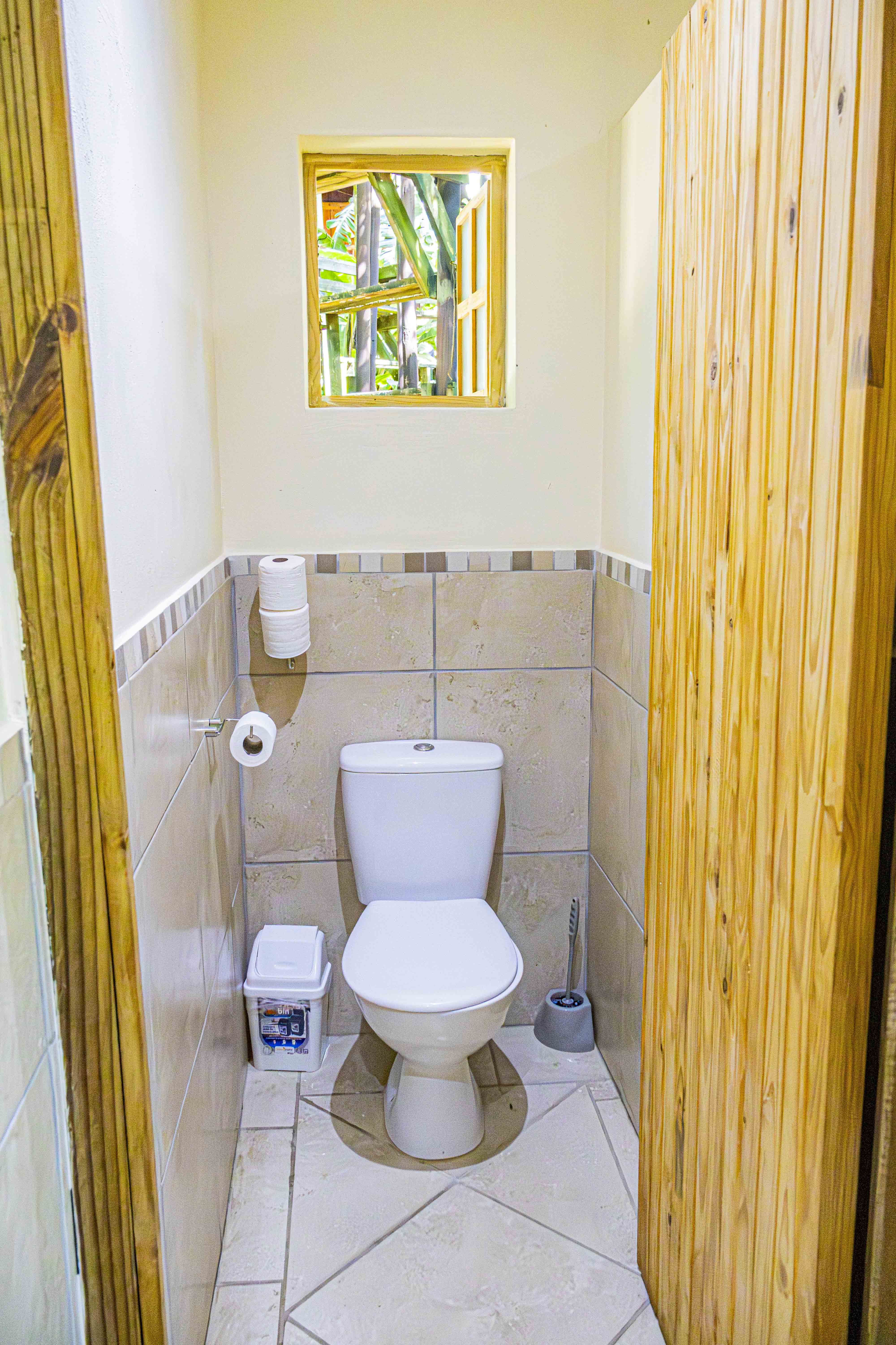 A toilet cubicle at Sugar Bay with a closed-lid toilet and wooden door.