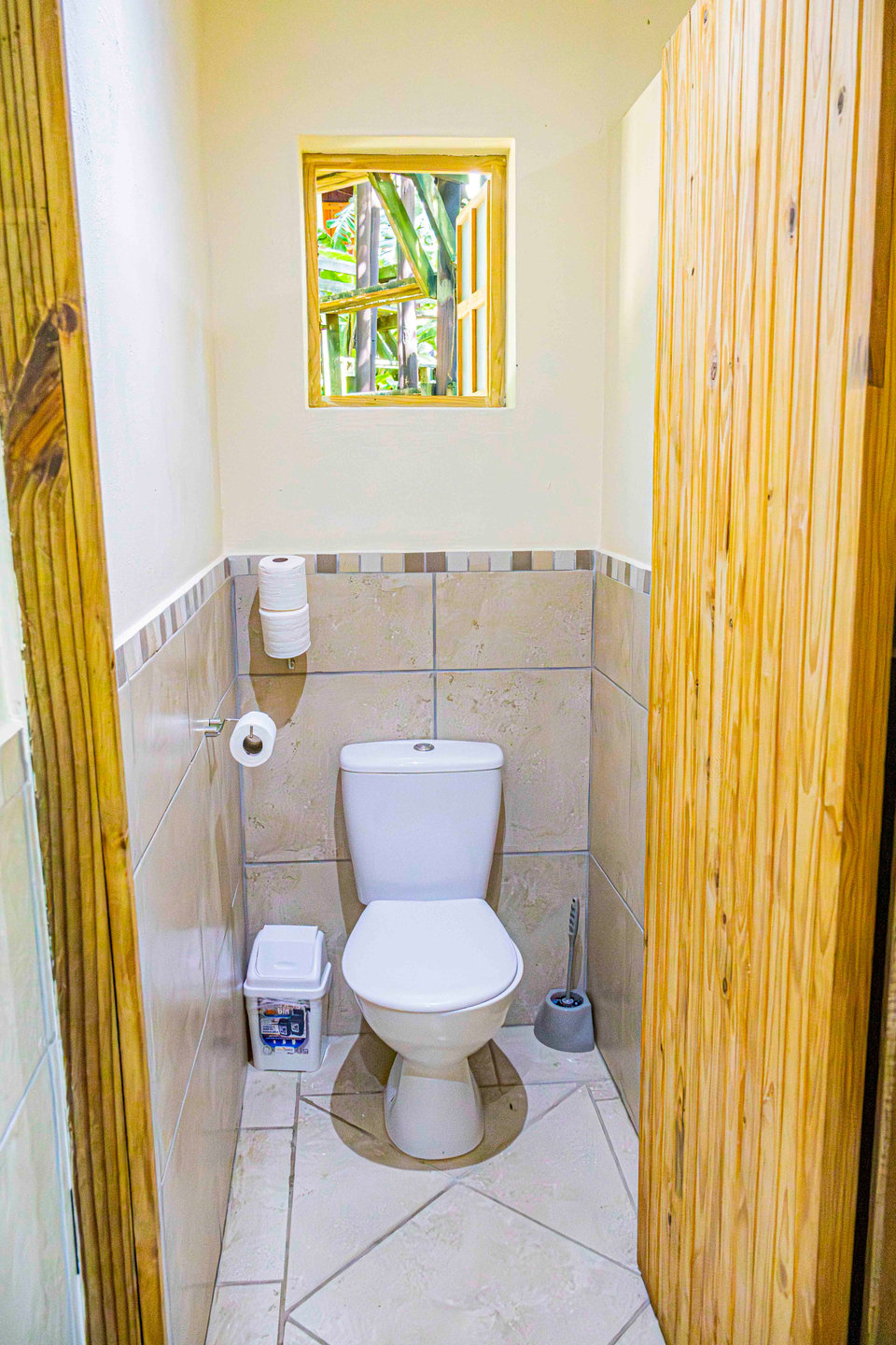 A toilet inside an individual cubicle with a wooden door.
