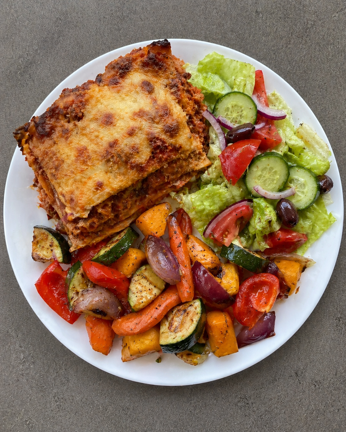 Lasagne served with roast vegetables and a side salad.