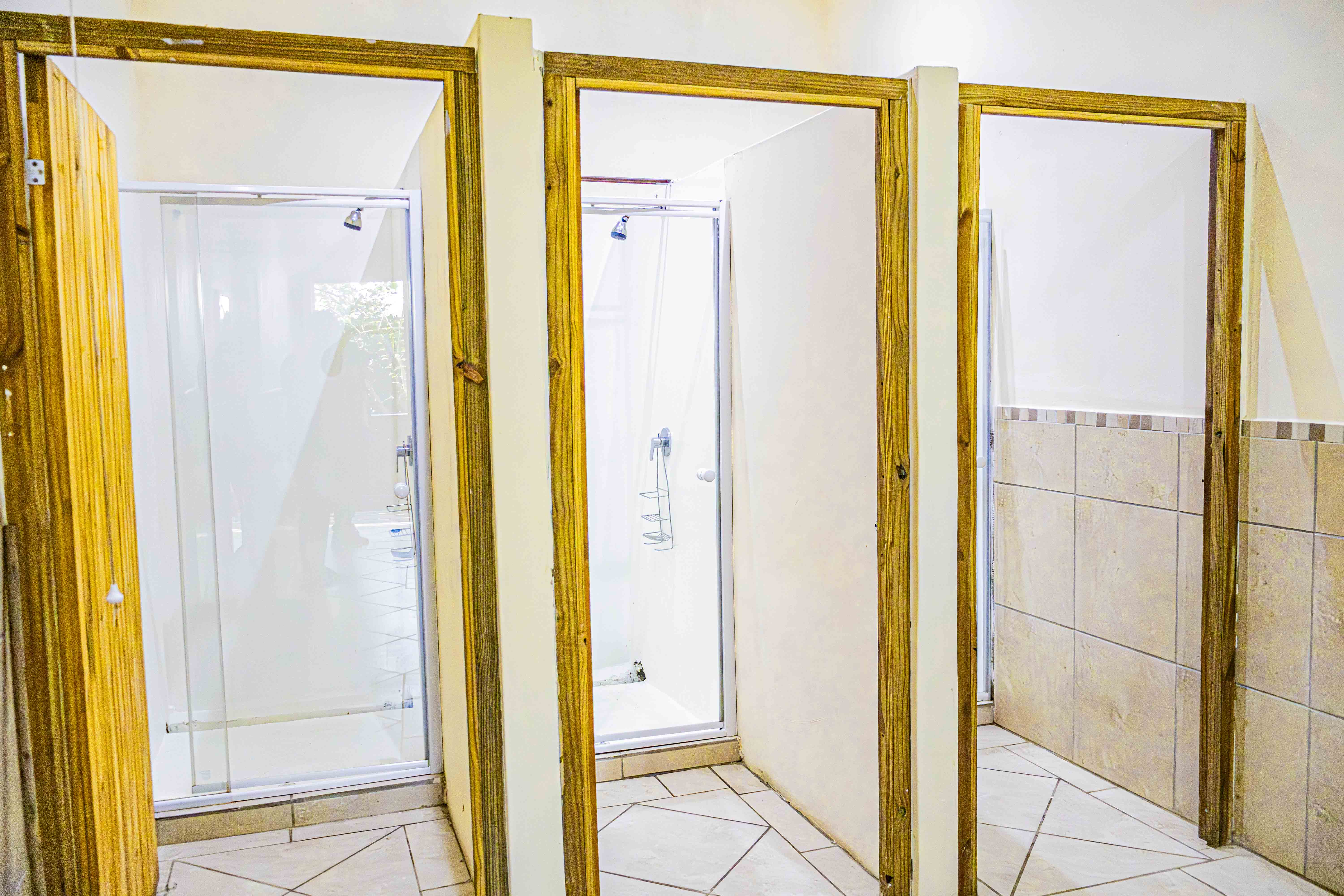 Shower cubicles at Sugar Bay, with glass shower enclosures and wooden doors.