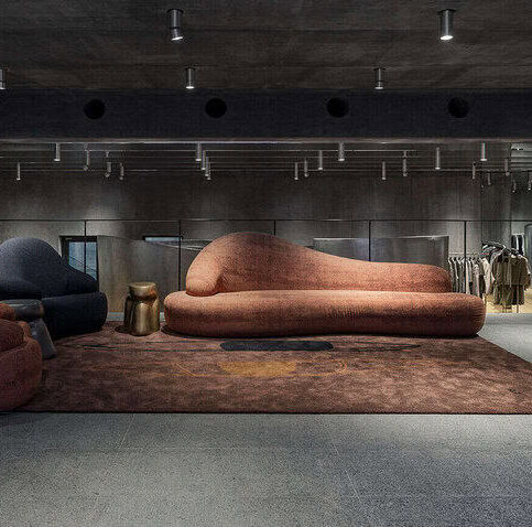 Interior of Wooyoungmi Seoul flagship in Itaewon featuring a minimalist sofa lounge, concrete walls, warm lighting, and quiet luxury design aesthetic.