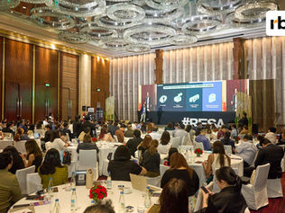 Wide-angle photo of a keynote speaker presenting Philippine economic and retail insights onstage at the rockbird media RESA summit, with delegates seated at round tables in a large ballroom.