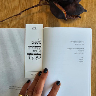 Bookmark inside book with Hebrew text, reading 'יום טוב' on wooden table background