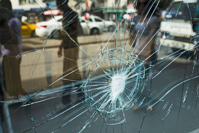 Cracked shopfront glass with street reflection