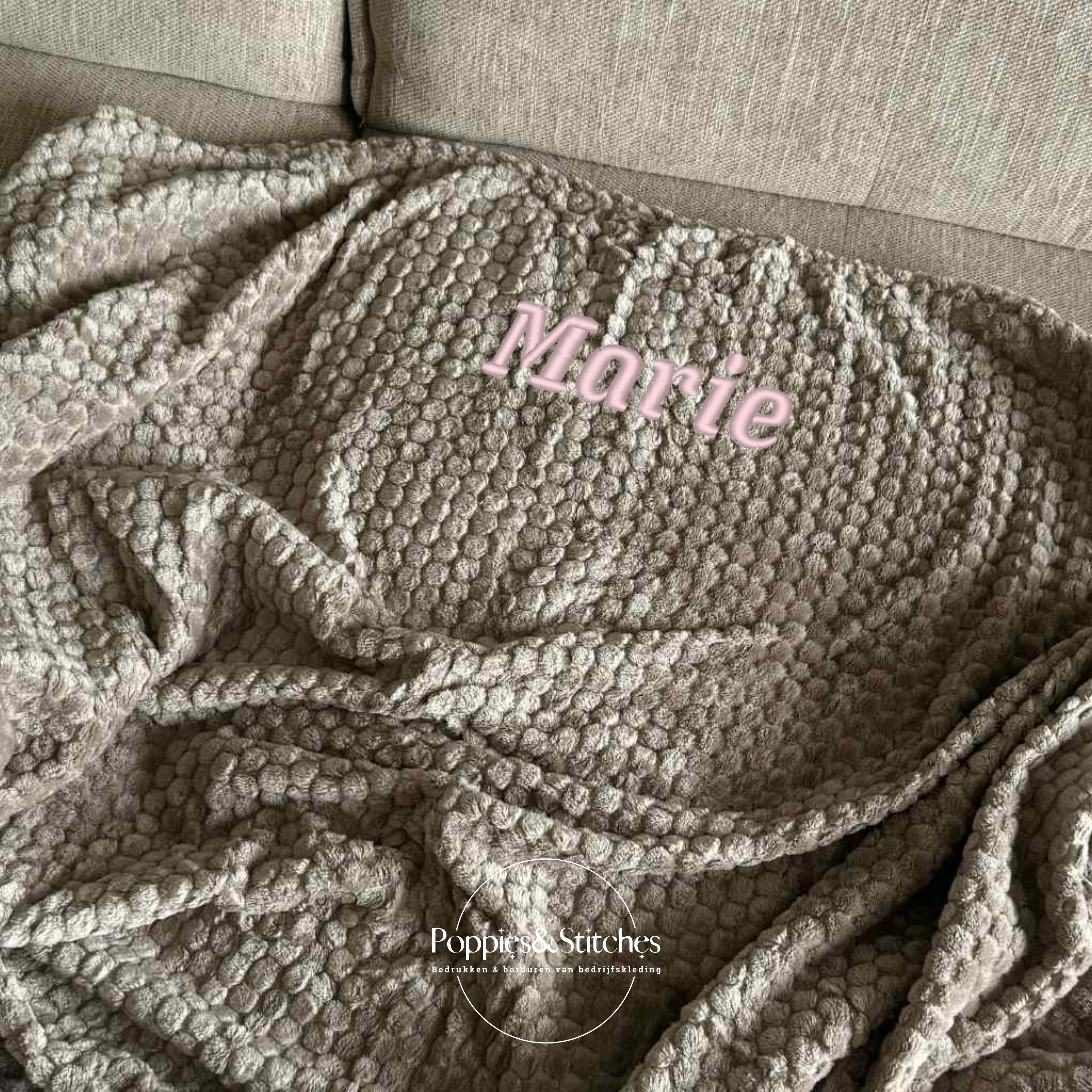 Zacht fleece dekentje in zandkleur, gepersonaliseerd met een geborduurde naam, ideaal als cosy plaid of persoonlijk cadeau.