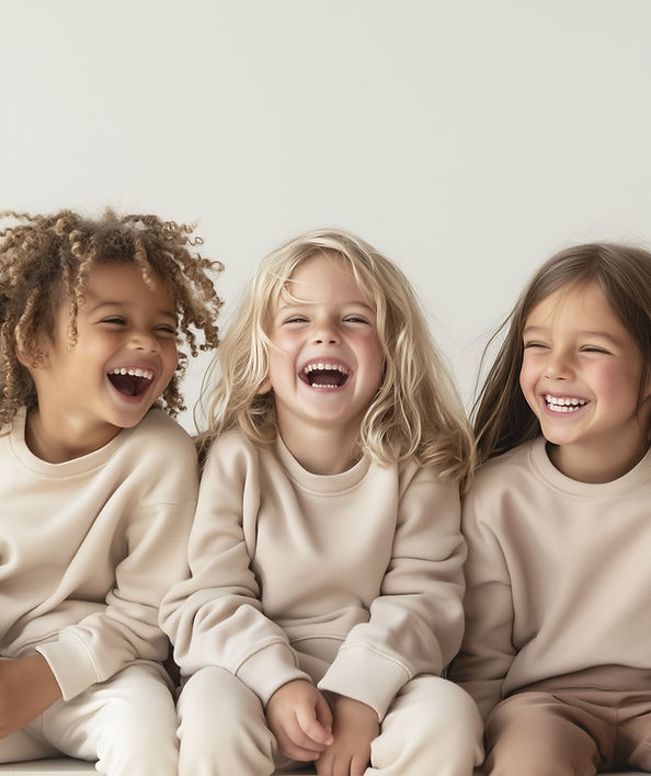 Three young children in matching cream sweatshirts laughing together