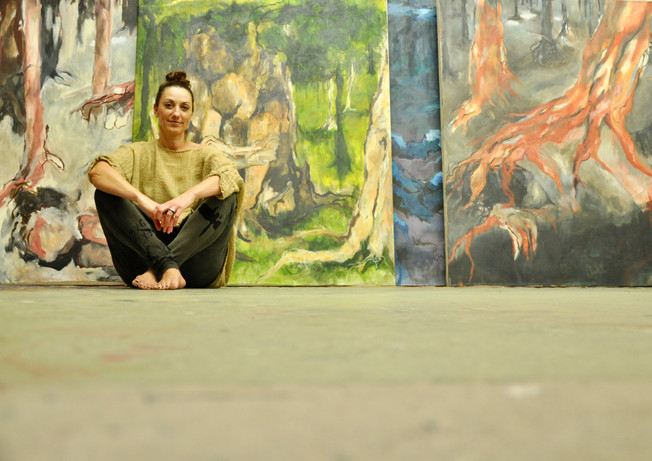 Chantal Hediger sitzt am Boden vor ihrem Bildern aus der Kollektion Living Nature oder auch Stumme Zeugen genannt. Die Bilder sind auf Rohleinen gemalt.