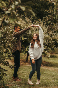 Couple cuddling in an apple orchard. The couples photos are taken at Held Companies in Corcoran, Minnesota by Kiera B. Photography.