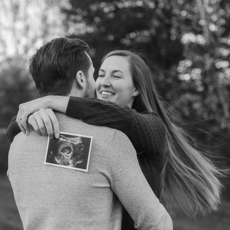 Kelsey and Laurence cuddling and laughing during fall couples session with ultrasound photo