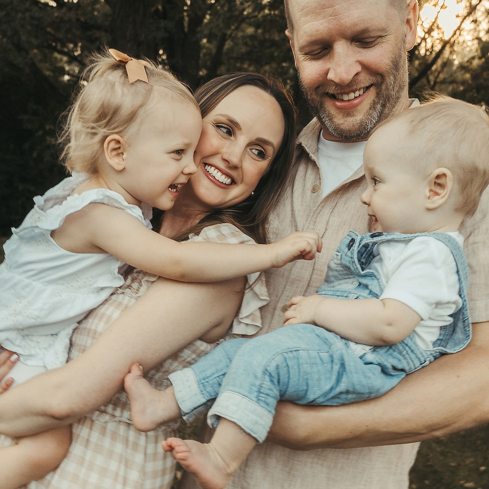 Mom and dad holding their two kids close in the park