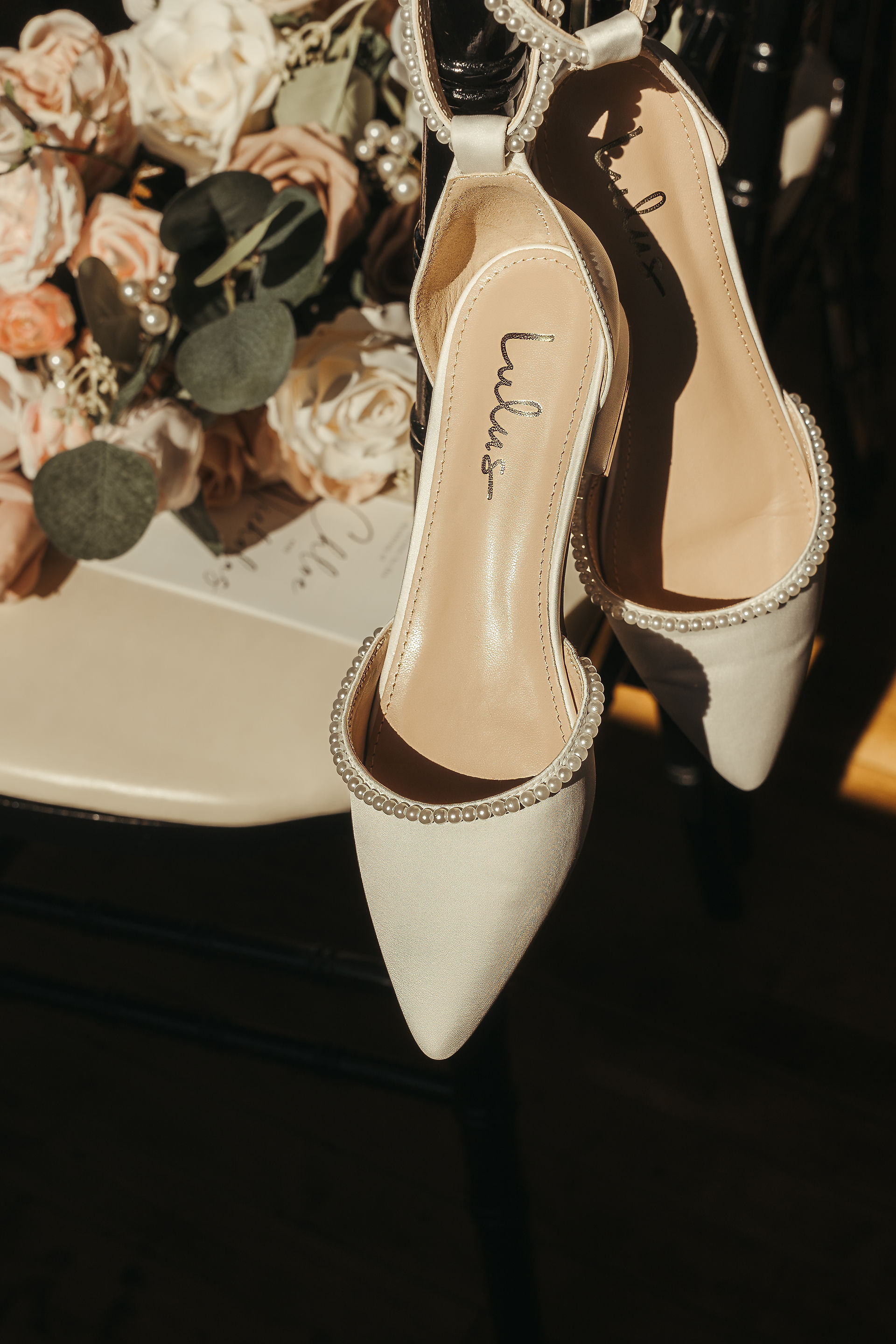 Detail photo of the brides shoes, bouquet, and wedding program on a chair