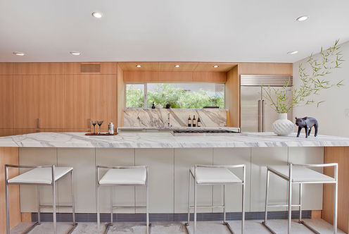 Modern kitchen with marble countertop, stools, and built in appliances, stylish design.
