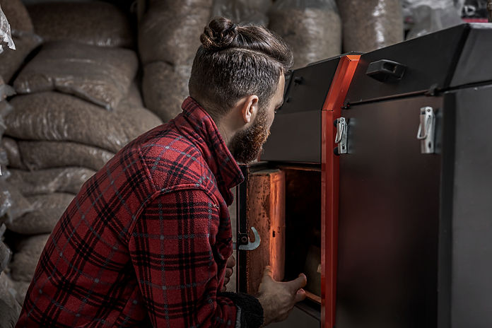 un-homme-dans-une-piece-avec-une-chaudiere-a-combustible-solide-travaillant-au-biocarburan