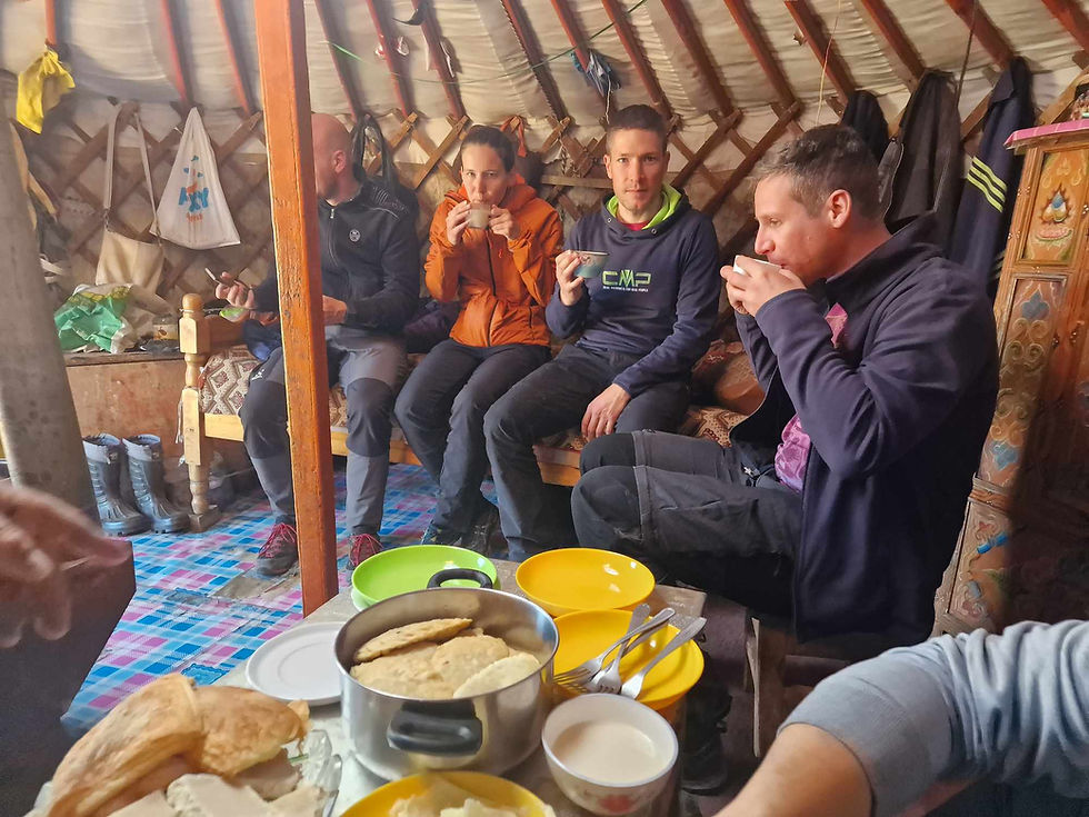 Foreign travellers seated at a table of Mongolian food inside a traditional ger with painted furniture