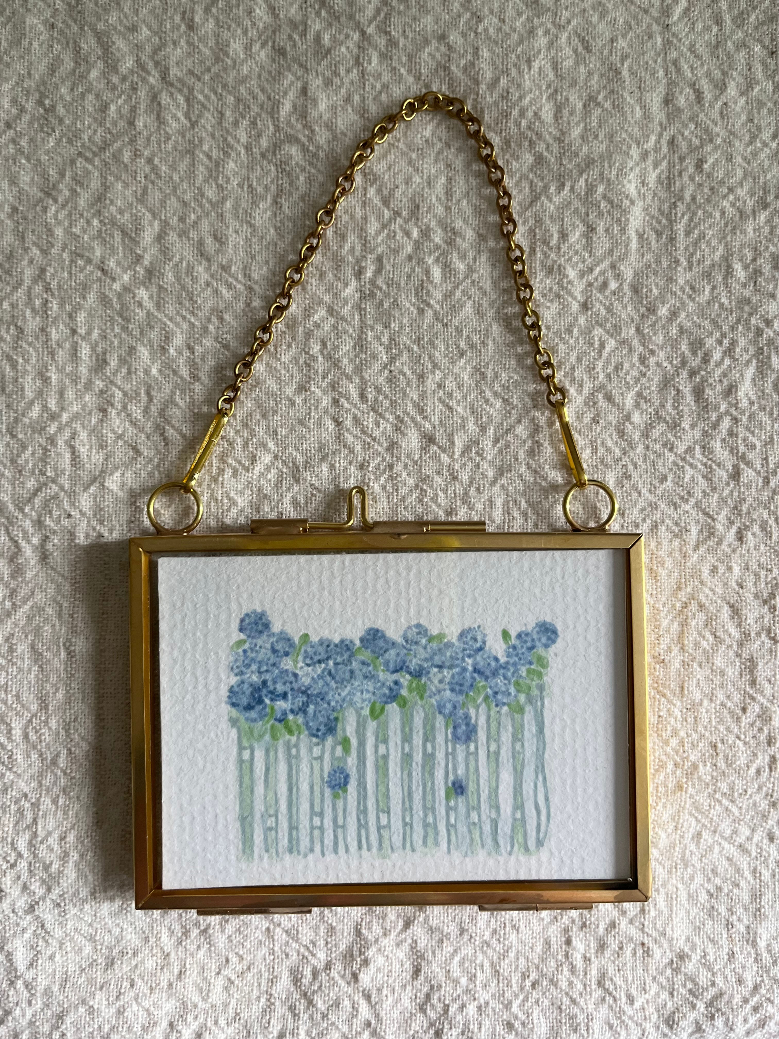 Floral art piece with blue flowers in a gold frame, hanging on wall.