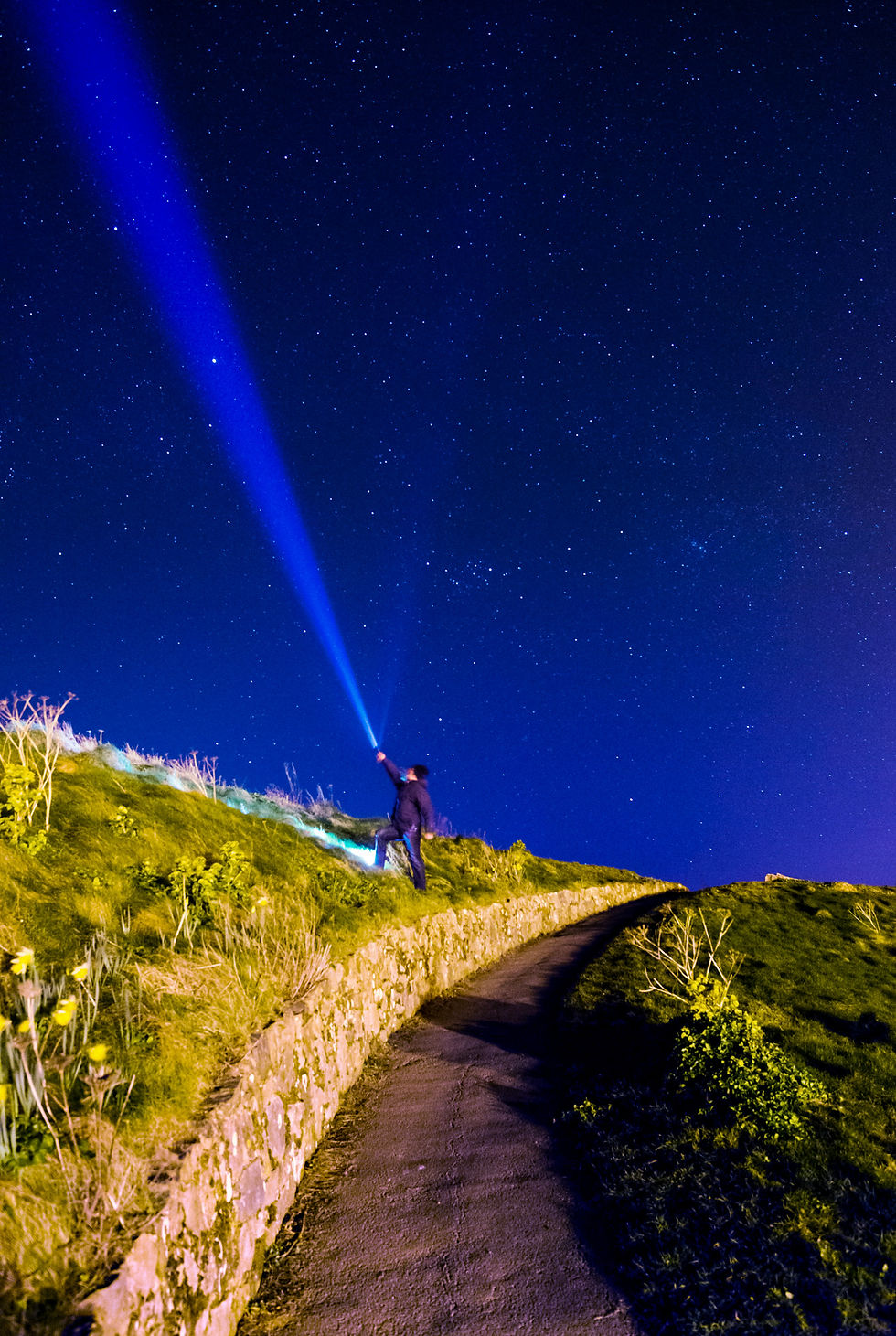 Man shining a torch upwards with stars in the background