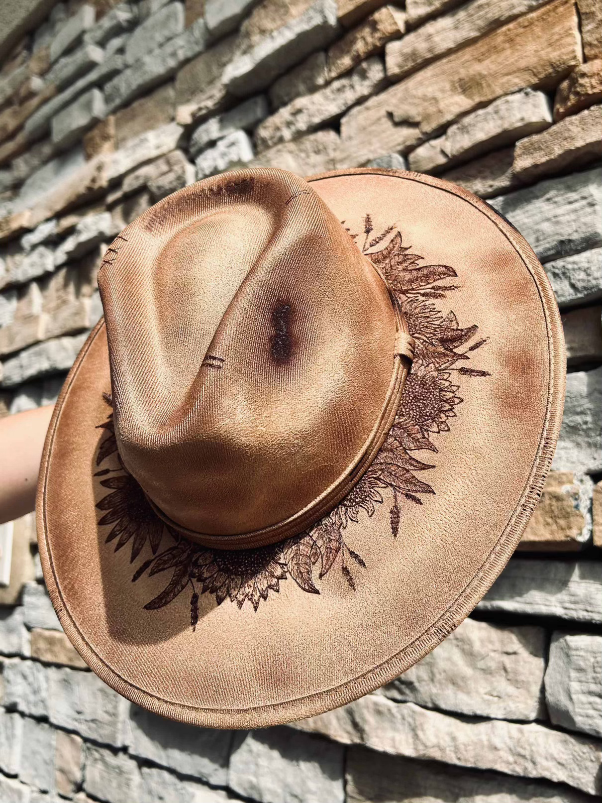 A light brown custom burned hat from Happy Harvest Co. has a mix of flowers around the crown of the hat.