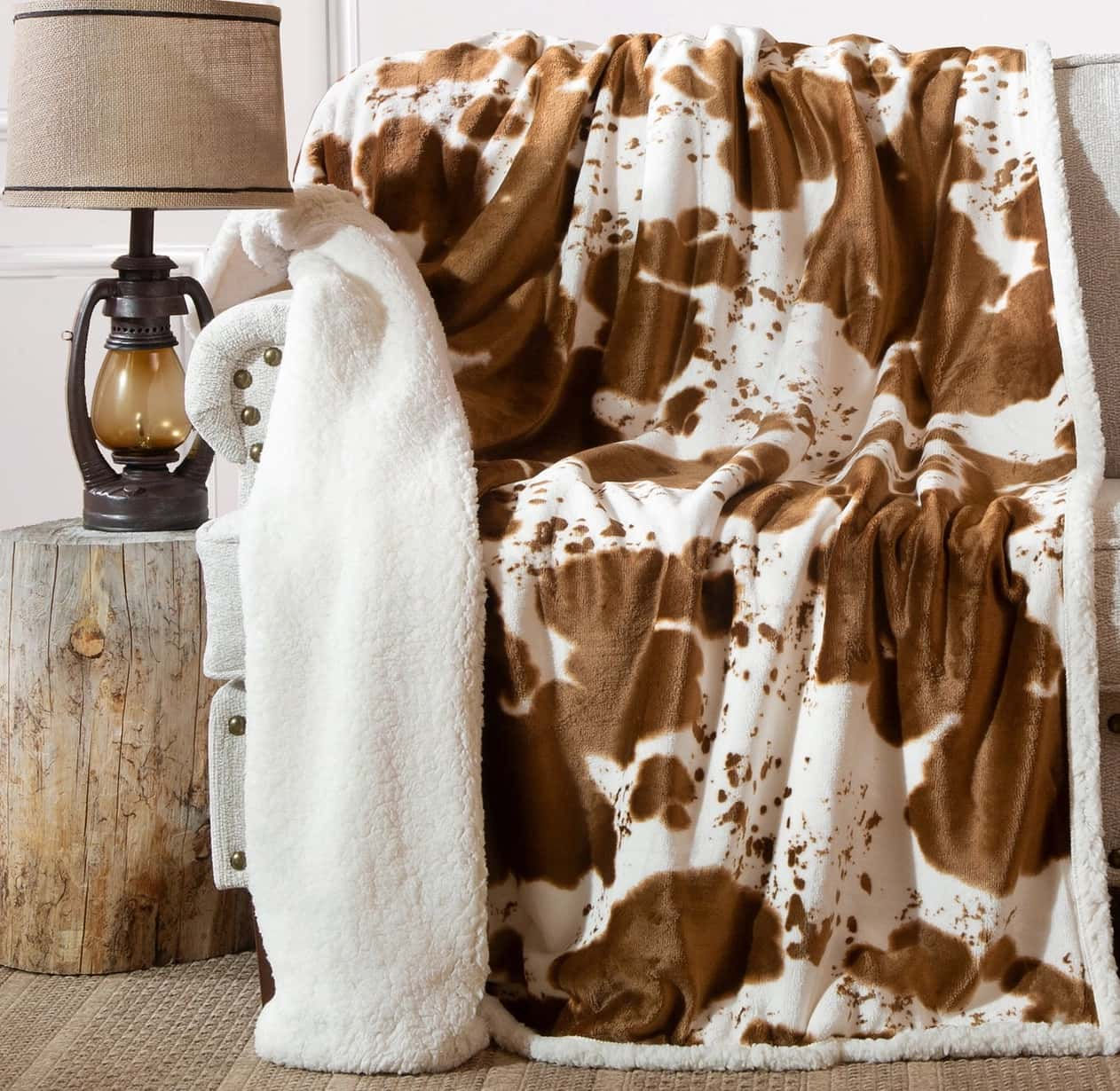 A Wrangler "Hair on Hide" sherpa blanket with cow print design sold by Happy Harvest Co.
