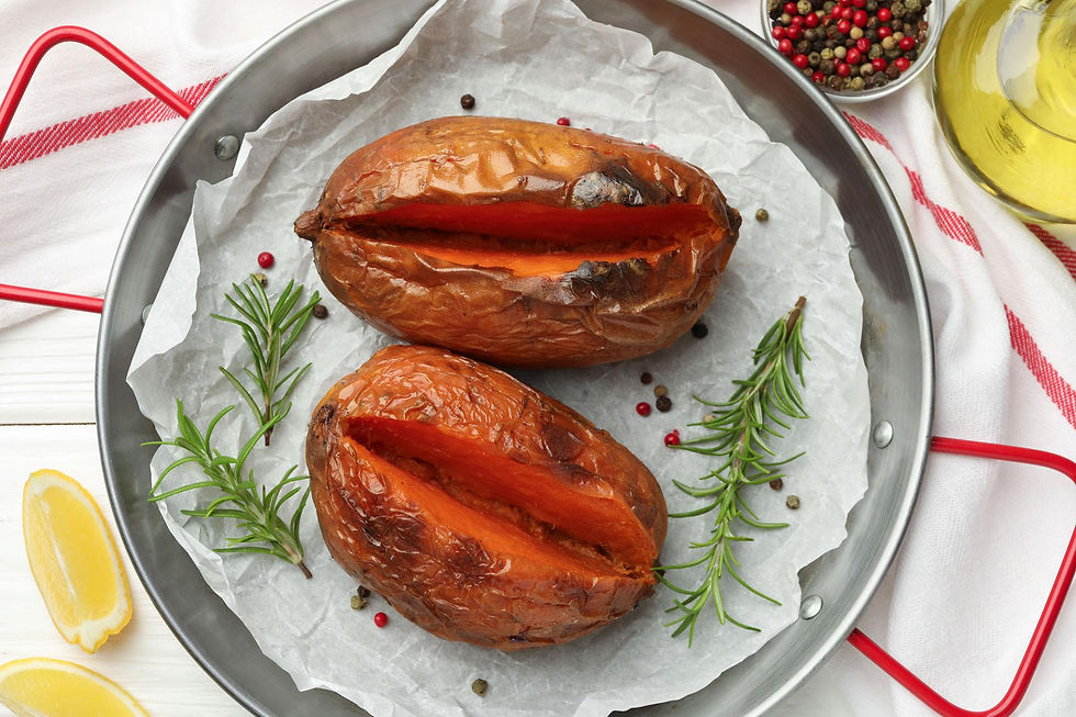 Roasted orange sweet potatoes split open in a pan lined with parchment paper.