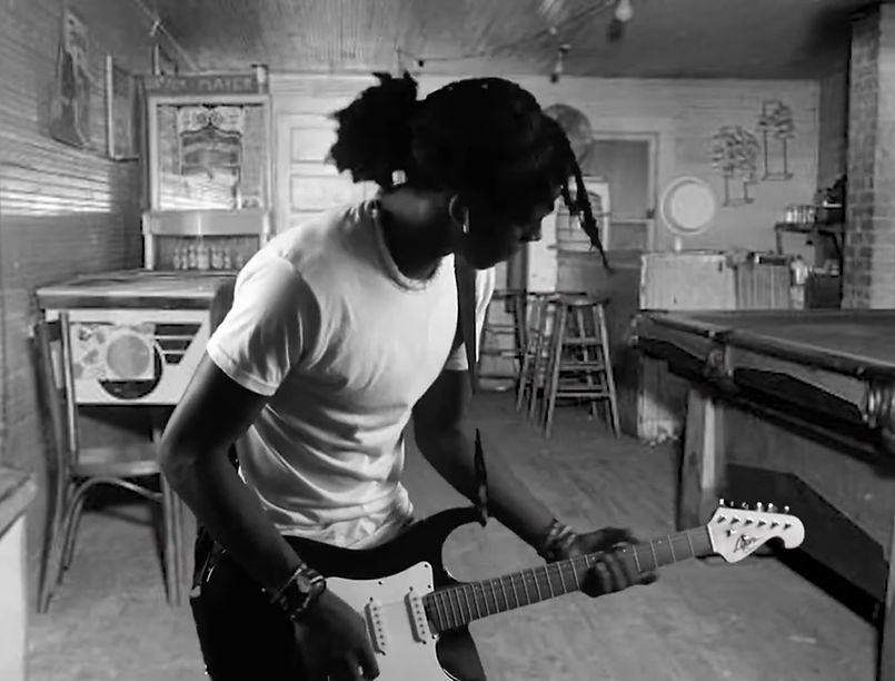 Young man with dreads plays guitar