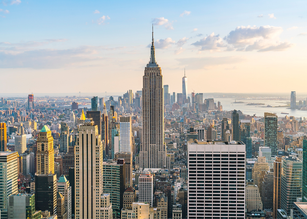 New York City skyline at sunset with the Empire State Building centered. Skyscrapers surround it under a partly cloudy sky. Calm mood.