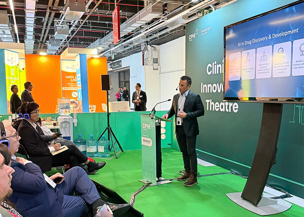 Man presents on "AI in Drug Discovery & Development" at a conference. Seated audience listening with headphones. Bright green, orange decor.