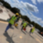 Workers in yellow vests and hard hats clean a construction site 