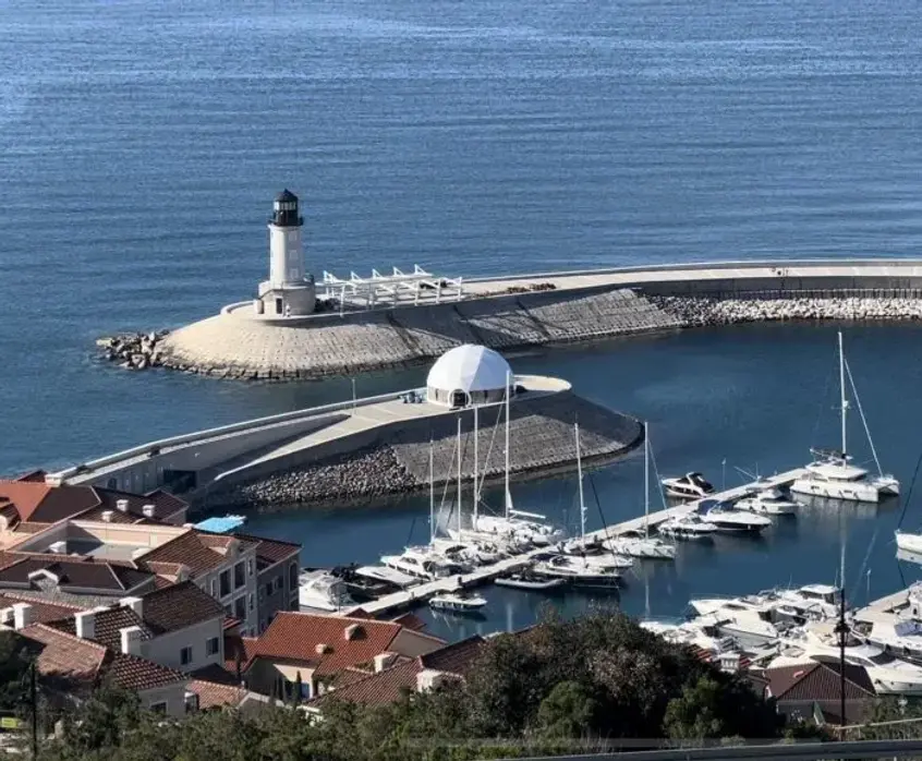 a large geodesic dome on a marina breakwater with sea view
