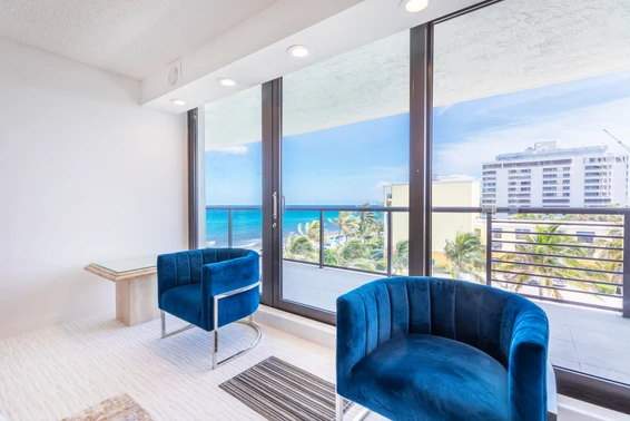 A modern bright white bed room with a panoramic view of the blue ocean