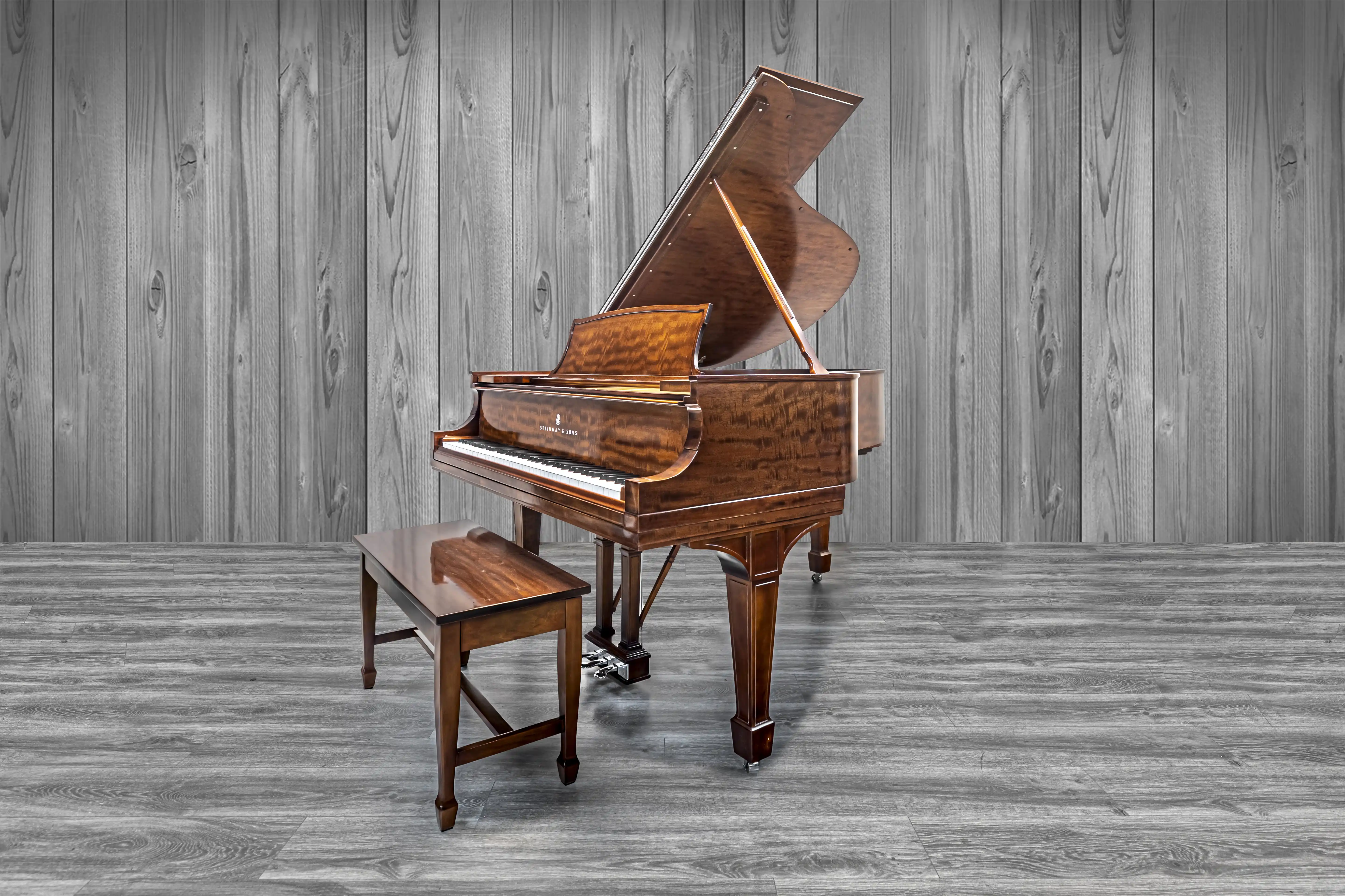 A product photo of a rosewood steinway baby grand piano on a wood floor and background