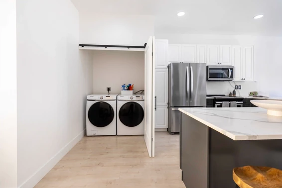 A laundry room with the door open next to a kitchen, located in a condo downtown Delray Beach Florida