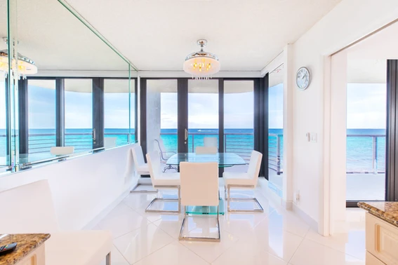 A modern bright white dining room with a panoramic view of the blue ocean on the beach in Delray